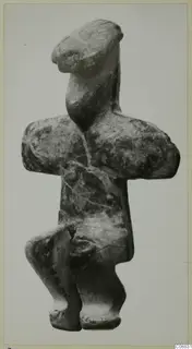 Stone figurine from Petra tou Limniti with arms folded across the chest, photographed against a plain background.