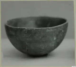 Pottery Red Polished III bowl, photographed from the side on a pale surface.