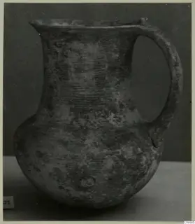 Jug with a flared mouth, a single strap handle and a rounded body, shown against a dark backdrop