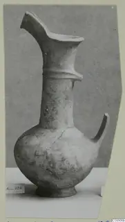 Pottery Base-Ring Ware jug with a flaring spout and a single handle, photographed against a grey backdrop