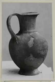 Pottery jug in Base-Ring Ware with a single loop handle, a flared neck and a ring foot