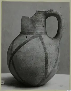 White Painted wheel-made jug with a broken rim, a single loop handle and dark painted bands on the body