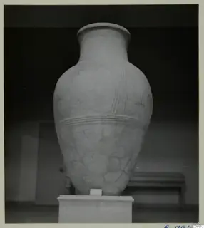 Large pottery pithos ware jar with raised ridged bands, standing on a white pedestal