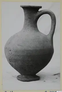 Plain pottery jug with a single loop handle, photographed on a pale background