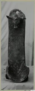 Pottery White Painted III-1: tall pottery object with a modelled animal head near the top and a trough-shaped base.