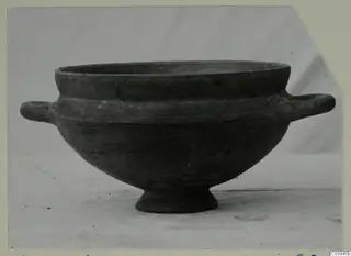 Footed bowl with two horizontal handles and a dark, smooth surface.