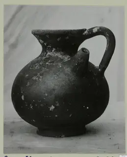 Dark-surfaced jug with a globular body, a side spout and a strap handle.