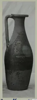 Pottery jug with a single strap handle and a long neck, photographed upright on a card mount