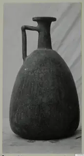 Jug with a single strap handle and a flat disc rim, photographed against a grey draped cloth