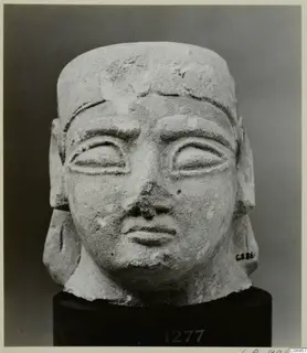 Limestone sculpture head, Neo-Cypriote, seen from the front on a dark stand