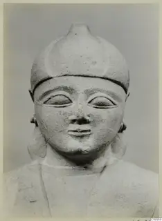 Limestone sculpture of a head and upper body with a rounded, pointed cap and large almond-shaped eyes