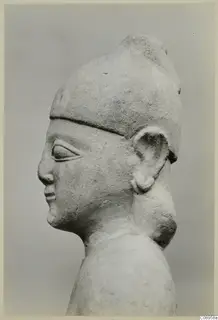 Limestone statue in side profile, head and upper body, wearing a tall cap-like headdress