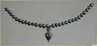 Necklace of ribbed beads with a vessel-shaped pendant hanging from the centre