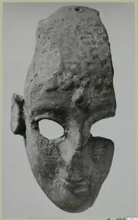 Terracotta face-shaped object with a large oval eye opening, a small ear on one side and a suspension hole at the top