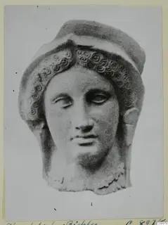 Terracotta head with spiral curls framing the face and a raised band above, on a photo mount
