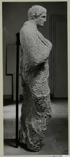 Limestone statue of a standing figure from Mersinaki, turned in profile and held on a black support rod