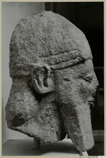 Limestone head of a figure wearing a banded cap, photographed in three-quarter view from the side