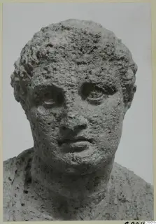 Limestone head of a male figure from Mersinaki, seen from the front with short curly hair