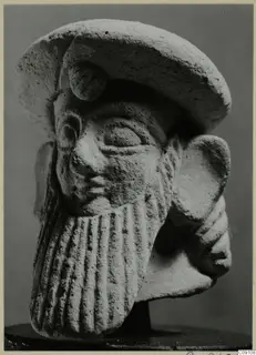 Terracotta Neo-Cypriote head of a bearded figure wearing a flat cap, shown on a dark stand