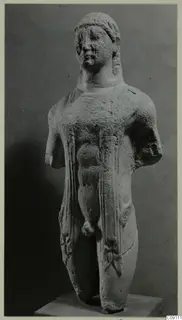 Limestone statue of a standing male figure with both arms broken off, set on a plain stone base