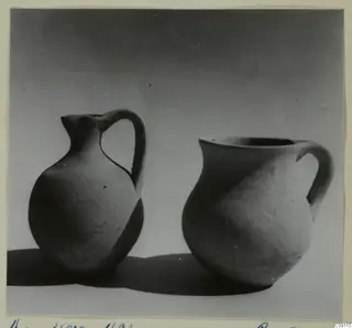 Two plain pottery vessels with handles, standing side by side