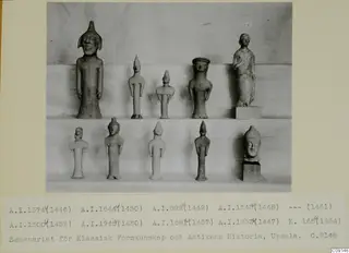 Ten clay statuettes of standing figures arranged on two shelves at Ayia Irini, photographed against a draped cloth.