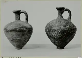 Two handled juglets with single loop handles, one with horizontal grooves and one with dotted decoration
