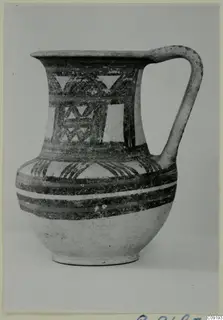 Painted pottery jug with a single handle, banded and triangular patterns in dark paint on a pale body.