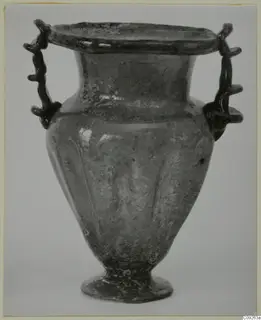 Blown glass vessel with two trailed handles, a flared rim and a ribbed body, shown against a pale background