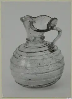 Blown glass jug with a looped handle and a wavy-rimmed spout, shown against a light grey backdrop.