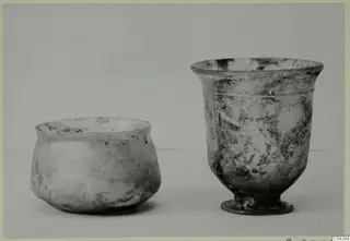 Two blown glass vessels: a squat jar on the left and a footed beaker with a flared rim on the right