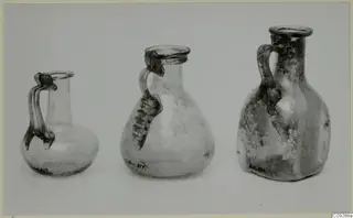 Three handled blown glass jugs shown side by side on a pale surface.