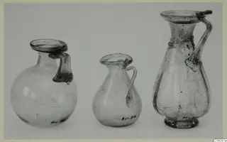 Three blown glass jugs with handles, one globular, one small and pear-shaped, one tall with a ringed neck