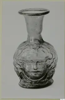 Blown glass flask with a moulded face on its body and a flared neck.
