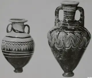 Two sand-core glass vessels, each with two loop handles; the left has a zigzag band, the right looping white trails