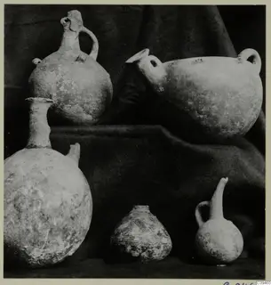 Five pottery vessels of different shapes arranged on dark draped cloth.