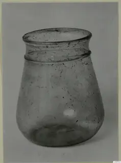 Blown glass jar with a flared rim and a ridged band below it, shown against a grey backdrop.