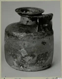 Blown glass jug with a flared rim and a ribbed handle, weathered and clouded.
