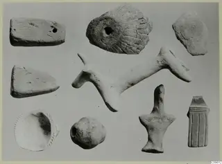 Nine pale objects and fragments on a grey background, including slabs, a shallow dish and a long rod-shaped piece.