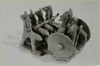 Terracotta group of figures on a rough base, with disc-shaped wheels and a long shaft, from Ayia Irini
