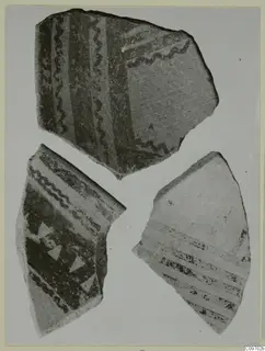 Three pottery sherds with dark painted wavy lines, bands and triangles on a light ground.