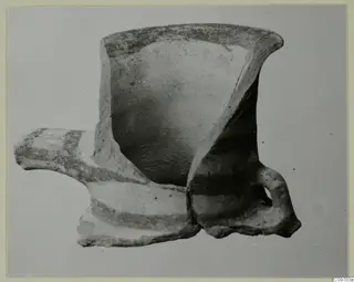 Fragmentary pottery vessel with a flaring rim, a horizontal spout to the left and a loop handle, painted with dark bands
