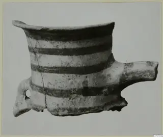 Pottery vessel with a flared rim, horizontal dark bands, a loop handle on the left and a tubular spout on the right