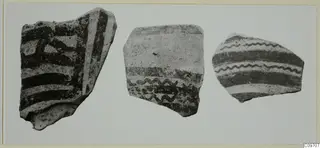 Three painted pottery sherds with dark bands and wavy lines, shown side by side.