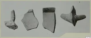 Four pottery sherds lying in a row on a grey surface, one with a projecting lug.
