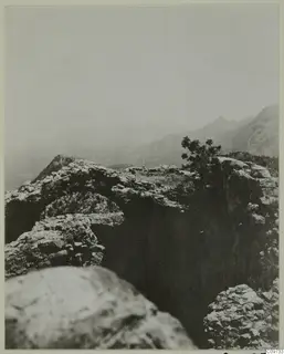 Rocky mountain landscape in the Kyrenia Mountains, with a bush on an outcrop and distant ridges fading into haze.