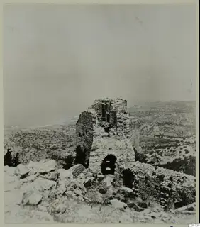 Ruined stone tower on a rocky hilltop with an arched doorway, overlooking scrubby hills and the sea in the Kyrenia Mountains