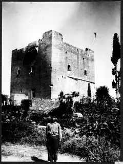Large square stone tower with battlements, with a boy standing in the foreground, Mesaoria