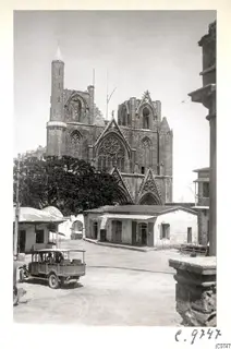Famagusta: Saint Nicholas cathedral facade with a rose window, with a car and people in the square in front.