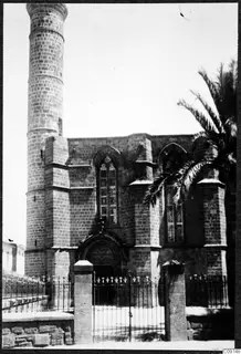 Stone building with a tall cylindrical tower, pointed-arched windows and an iron gate, Nicosia.